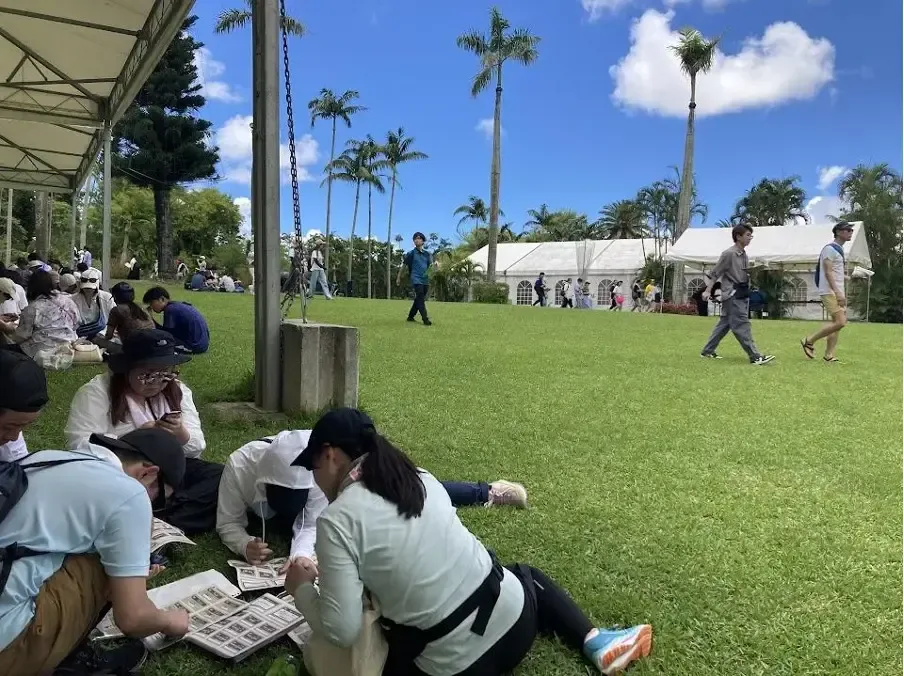 芝生の広場に座って謎解きを進める参加者
