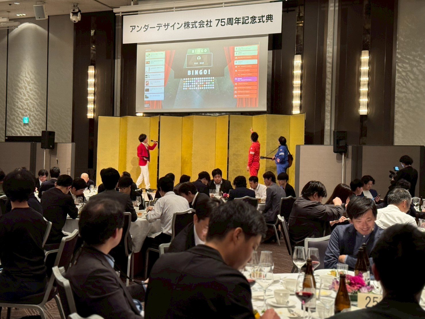 スクリーンにビンゴの数字が映し出された会場の様子