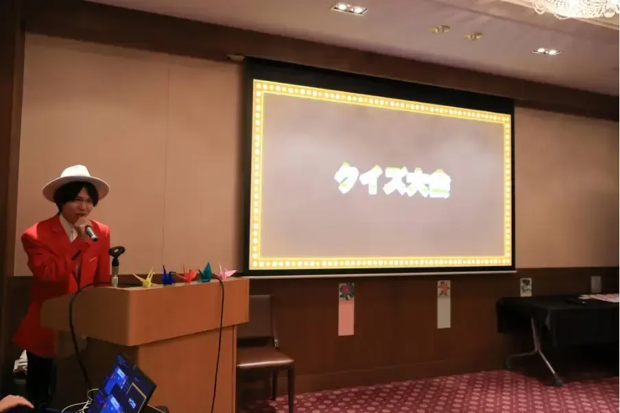 スクリーンに「クイズ大会」のタイトルが映るステージとMC