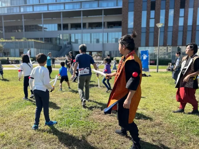 芝生の広場で武将姿のパフォーマーと参加者が交流する様子