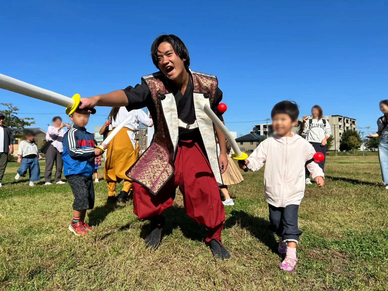 武将姿のパフォーマーと一緒にチャンバラ合戦を楽しむ子どもたち